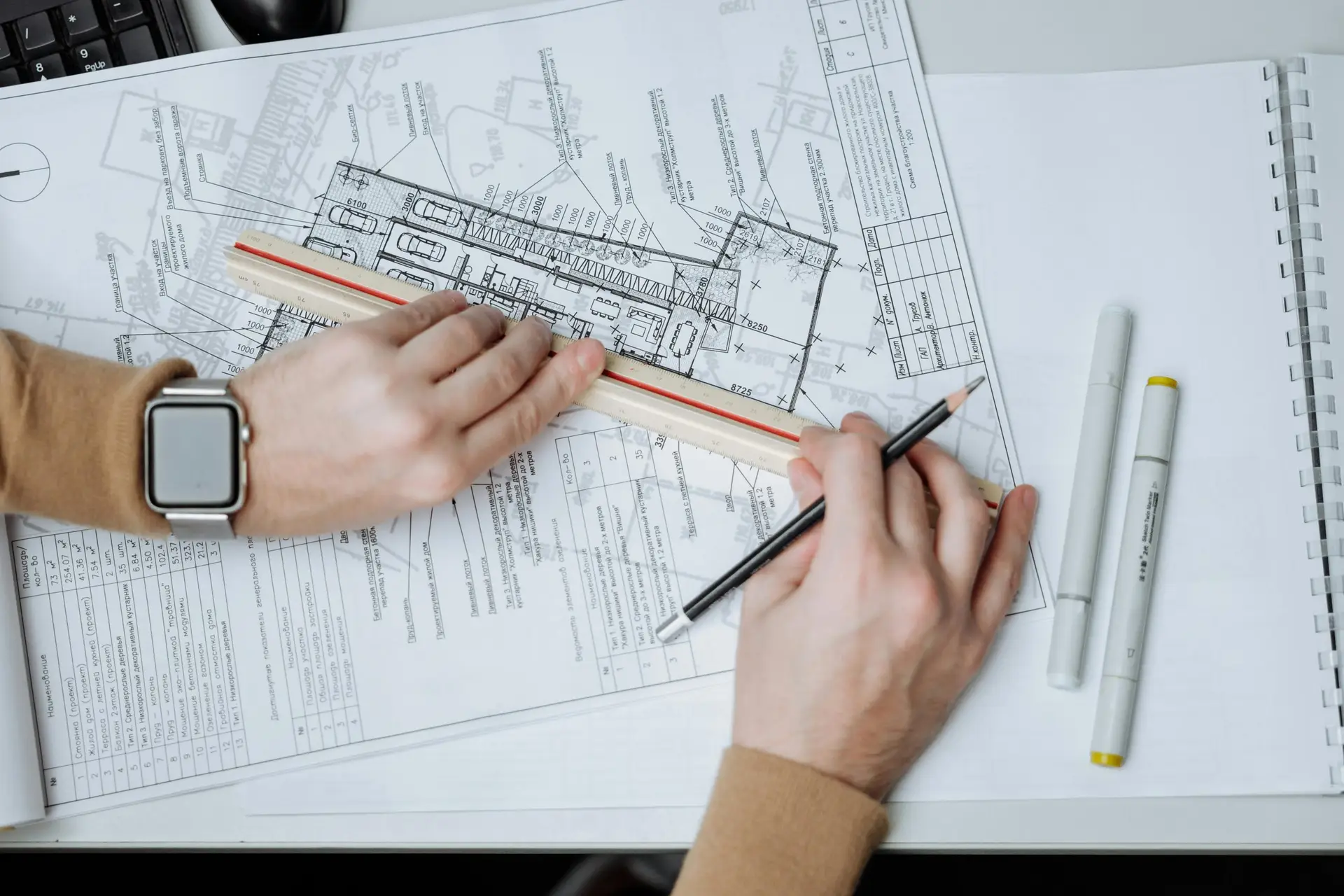 An architect uses a ruler and pencil on blueprints, showcasing workspace and planning.